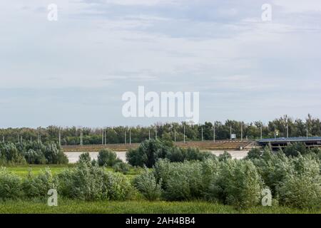 Straße Brücke, die durch ein Feld mit Bäumen und Sträuchern. Panorama. Stockfoto