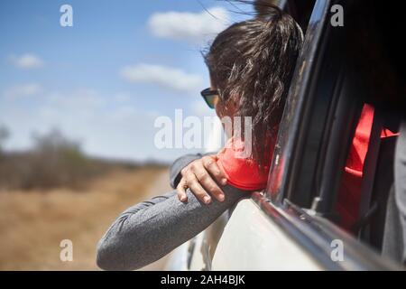 Frau bewundern Sie die Landschaft mit dem Kopf aus dem Autofenster, Krüger Nationalpark, Südafrika Stockfoto