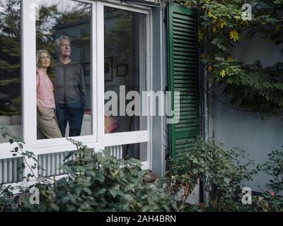 Senior Paar hinter Fensterglas von zu Hause aus suchen Stockfoto
