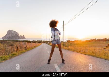 Junge Frau steht auf der Straße und den Sonnenuntergang beobachten, Ibiza Stockfoto