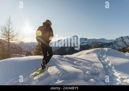 Frau wandern mit Schneeschuhen in den frischen Schnee in die Berge bei Sonnenuntergang, Valmalenco, Italien Stockfoto