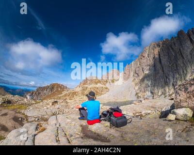 Älterer Mann mit einer Unterbrechung von Wandern in der Berglandschaft, Fleimstaler Alpen, Trentino, Italien Stockfoto