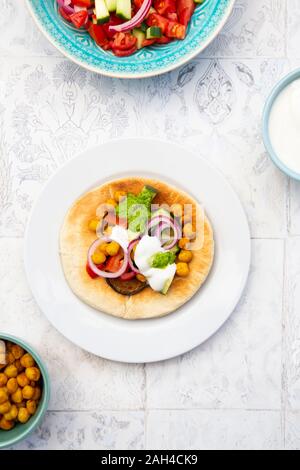 Israelische sabich mit pita Brot, Aubergine, Kichererbsen, Zwiebeln, Tomaten, Gurken, Joghurt und zhug Sauce Stockfoto