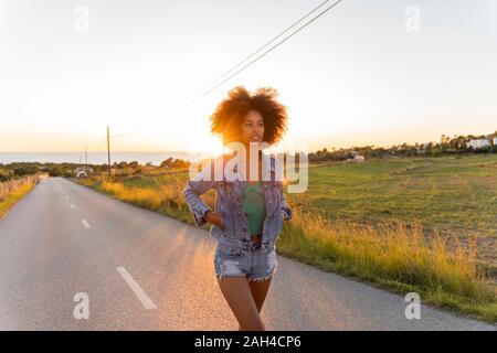 Junge Frau zu Fuß auf der Straße bei Sonnenuntergang, Ibiza Stockfoto