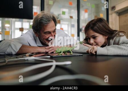 Senior buisinessman und Mädchen spielen mit Chameleon Figur im Büro Stockfoto