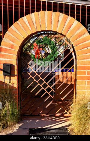 Red brick Bogen mit einem schmiedeeisernen Tor mit einem weihnachtlichen Kranz Aufhängen von Tubac, Arizona Stockfoto