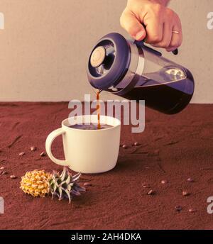 Männliche Hand hält französische Presse und gießt Kaffee in eine Tasse Stockfoto