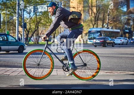 Ein Radfahrer in der Stadt geht auf einen Fußgängerüberweg. Umweltfreundliche Verkehrsträger. Fahrrad mit fester Drehzahl Stockfoto