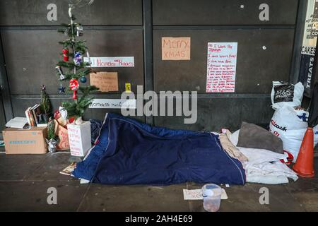 Central London, London, 24. Dezember 2019. Momente weg von Downing Street, Westminster Tube Station von einem Obdachlosen behelfsmäßige Unterkünfte und Verschieben von Nachrichten an der Wand, sowie ein kleines Regal mit Büchern und anderen 'Komfort' an Heiligabend. Die Zahl der Haushalte neu Obdachlose in den letzten 12 Monaten zugenommen hat, und in London, das wachsende Problem ist vor allem die Zahl der Obdachlosen in neue Höhen schnellte sichtbar. Credit: Imageplotter/Alamy leben Nachrichten Stockfoto