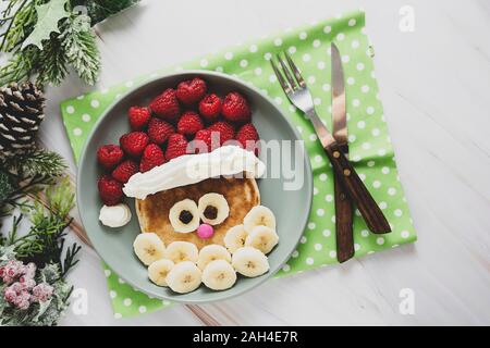 Spaß Essen für Kinder. Weihnachten Santa Pfannkuchen mit Himbeeren und Banane für Kinder Menü, Ansicht von oben mit der Kopie. Stockfoto