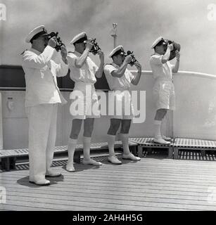 1950er Jahre, historische, ein Kapitän und drei uniformierte Crew stehen auf dem Deck des Dampfers mit traditionellen Messgeräte, Sextanten, des Schiffes Kurs navigieren. Sextanten sind maritime Messgeräte können Sie den Winkel zwischen dem Horizont und einem Himmelskörper wie Sonne, Mond oder Sterne zu bestimmen. Stockfoto