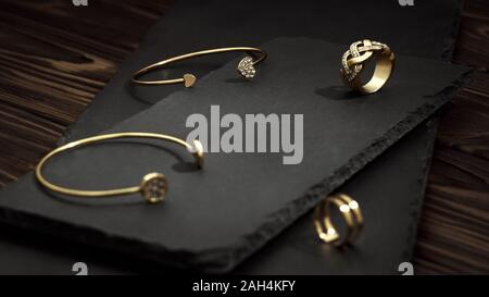 Golden mit Diamanten Armbänder und Ringe am Schwarzen Stein Platten auf Holz- Oberfläche Stockfoto