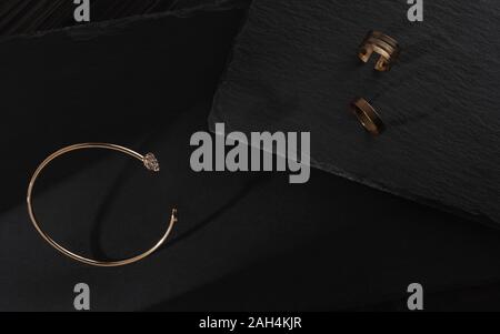 Golden mit Diamanten Armband und goldene Ringe an dunklen Stein Hintergrund Stockfoto