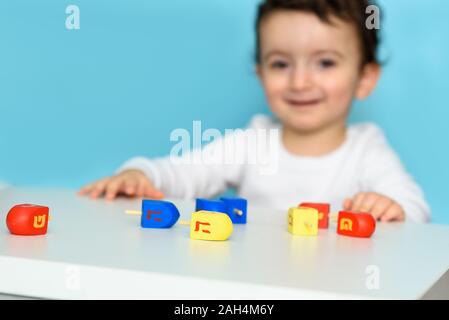 Kleine jüdische Junge spielt mit bunten Holz Dreidel. Selektiver Fokus auf Bewegung. Stockfoto