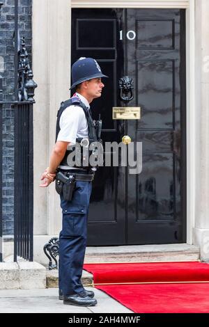 Polizisten vor der schwarzen Tür der Nr. 10 Downing Street, London, England, Vereinigtes Königreich Stockfoto