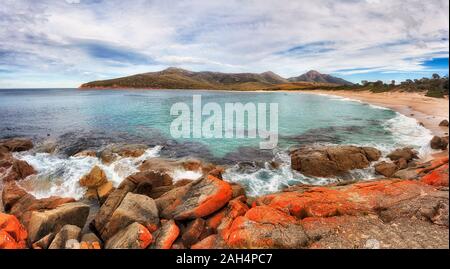 Red erodiert Felsbrocken um WIneglass Bay und White Sand Beach in Freycinet National Park in Tasmanien an einem sonnigen Tag - Wide Panorama. Stockfoto