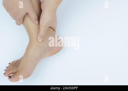 Closeup Frau hält Knöchelschmerz auf weißem Hintergrund. Gesundheit und medizinische Konzept. Stockfoto