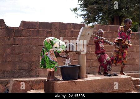 Drei Kleine afrikanische Mädchen, Die Stolz Darauf Sind, Erfolgreich Wasser Aus einem Dorfborehole Zu Pumpen Stockfoto