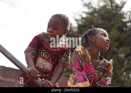 Zwei Kleine Afrikanische Mädchen, Die Sich Bemühen, Wasser Aus Dem Öffentlichen Bohrloch Zu Pumpen Stockfoto