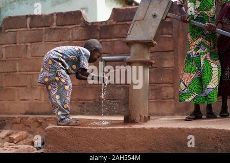 Little African Boy Trinkt Frisches Wasser Aus Dem Dorfborehole Stockfoto