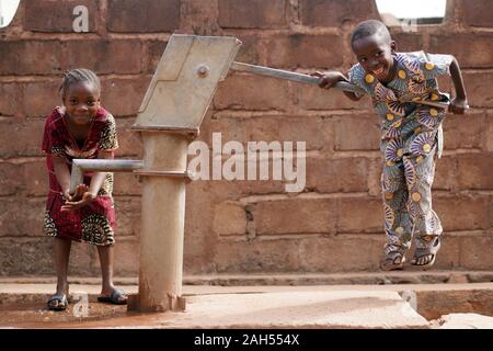 Happy Little African Boy Pumpt Wasser Für Seine Schwester Stockfoto