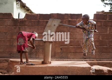 Kleiner afrikanischer Junge, Der Versucht, Wasser aus dem Dorf Gut Zu Pumpen Stockfoto