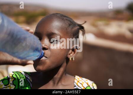 Nahaufnahme einer afrikanischen Mädchen mit Ohrringe Trinkwasser direkt aus einem großen Plastikflasche Stockfoto