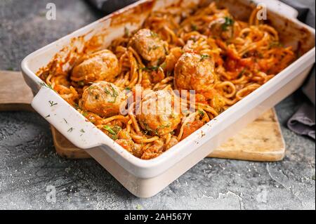Close-up Spaghetti mit Fleischbällchen mit Tomaten und Kräutern in einer Auflaufform. Traditionellen italienischen Pasta. Mediterrane Küche Stockfoto