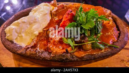 Iskender Kebap, gegrilltes Fleisch vom Spieß mit getränkten Türkisches Fladenbrot unter einer dicken Schicht Tomatensauce mit einem großen Splash von Joghurt, garniert Stockfoto