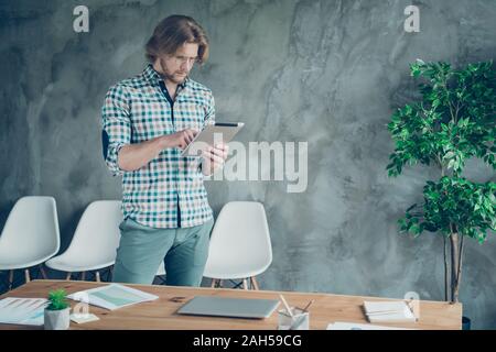Portrait von fokussierte Person tragen Brillen Brillen karierten Plaid Shirt mit modernen, Technologie stehen im Innenraum Stockfoto