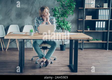 Volle Größe Foto von gleichgesinnten Freelancer in Gedanken sitzen auf Stuhl tragen, Brillen Brillen karierten Plaid Shirt Hose in Loft Stockfoto