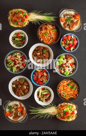 Sortiment von thailändischen Gerichten in Schalen auf einem schwarzen konkreten Hintergrund gekocht. Ansicht von oben. Stockfoto