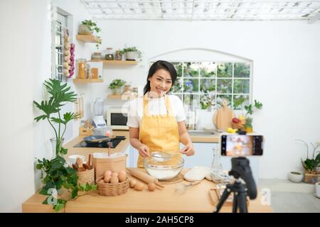 Hübsche junge asiatische Frauen Lebensmittel Blogger an einem neuen Video- und erklären, wie ein Gericht zu kochen Stockfoto