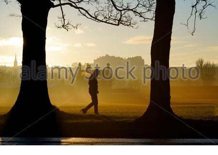 Edinburgh, Schottland, Großbritannien. 25. Dez 2019. Kalt, klar und hell mit geringer Masse Nebel am Weihnachtstag bei Sonnenaufgang in Inverleith Park, mit Blick auf das Edinburgh Castle. Menschen auf dem Weg in den Park. Quelle: Craig Brown/Alamy leben Nachrichten Stockfoto