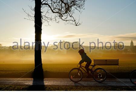 Edinburgh, Schottland, Großbritannien. 25. Dez 2019. Kalt, klar und hell mit geringer Masse Nebel am Weihnachtstag bei Sonnenaufgang in Inverleith Park, mit Blick auf das Edinburgh Castle. Kind auf dem Fahrrad. Quelle: Craig Brown/Alamy leben Nachrichten Stockfoto