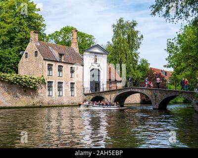 Boot mit Menschen, Brücke über den Kanal und Eingangstor zum Begijnhof, Beginenhof, in der Altstadt von Brügge, Belgien. Stockfoto