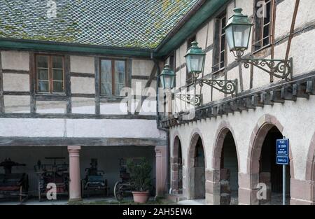 Ungersheim, Oberrhein/Frankreich - 13. Dezember, 2019: Blick auf das historische Fachwerkhaus elsässischen Land Haus und Hof mit alten Pferdekutschen carria Stockfoto