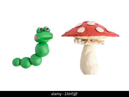 Caterpillar und amanita aus Plastilin Zicklein auf weißem Hintergrund geformt. Plastilin Caterpillar und Pilz aus Plastilin Stockfoto