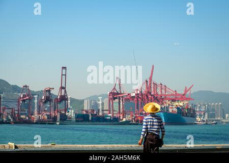 Fisher Mann mit Angelrute von hinten in der Nähe der Container schiff und Fracht Hafen in HongKong Stockfoto