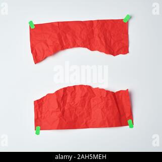 Zerknitterte rotes Blatt A4-Papier zur Hälfte abgerissen und mit grünem Klebeband auf einem weißen Hintergrund geklebt, Element für einen Designer Stockfoto