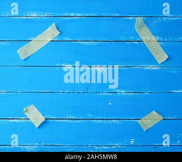 Vier Papier, Gelb Stück Klebeband an den Ecken auf einem blauen Hintergrund Holz befestigt, Nachahmung der Befestigung ein Blatt Papier, leeren Raum Stockfoto