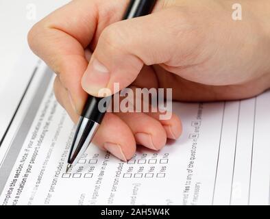 Hand mit Stift über leere Kontrollkästchen im Antragsformular Stockfoto