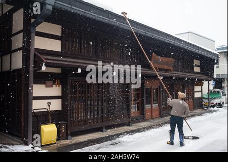 28.12.2017, Takayama, Gifu, Japan, Asien - ein Mann löscht den Schnee vom Dach eines Hauses mit einer langen schneeschaufel Lawinen zu verhindern. Stockfoto