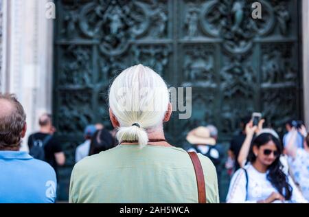 Touristen schätzen die schönen Reliefs auf der bronze Tür des Gebäudes der Mailänder Dom (Duomo di Milano), der Kathedrale Kirche von Mila Stockfoto