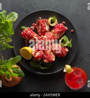 Granatapfel Obst auf schwarzem Teller, Glas Granatapfelsaft und Zitrone, Ansicht von oben Stockfoto