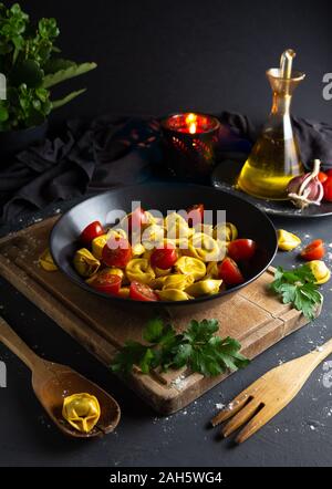 Ravioli mit Tomaten auf schwarzem Teller hausgemachte Speisen in rustikaler Umgebung, Luftaufnahme, dunklen Essen Stockfoto