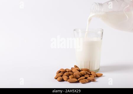 Vegan Mandelmilch ist aus einer Flasche in ein Glas auf einem weißen Hintergrund gegossen Stockfoto