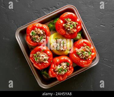 Rote Paprika mit Hackfleisch, Reis, Zwiebel auf schwarzen Stein Hintergrund gefüllt. Ansicht von oben, flach Stockfoto