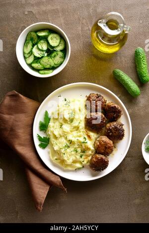Hackfleisch Schnitzel mit Kartoffelbrei auf weißen Platte über braunen Hintergrund. Ansicht von oben, flach Stockfoto