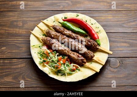 Türkische Adana Kebab mit frischem Gemüse auf fladenbrot über Holz- Tabelle. Lecker essen im arabischen Stil Stockfoto